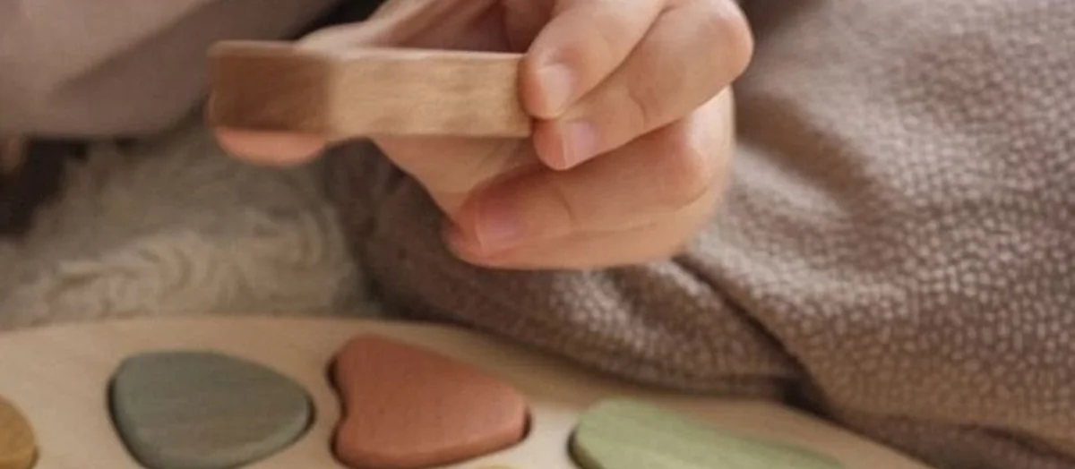 Primo piano di una mano che regge un blocchetto di legno su un tessuto morbido: ogni articolo viene controllato e sanificato